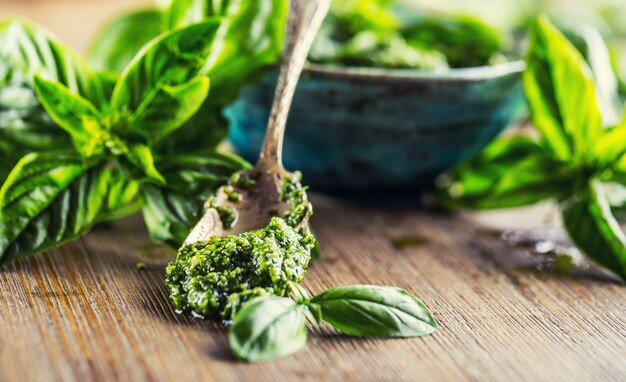 Fresh basil leaves pesto on wooden table.