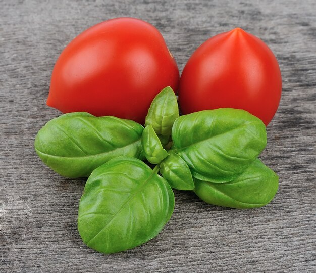 Foglie di basilico fresco e pomodori sui tavoli di legno