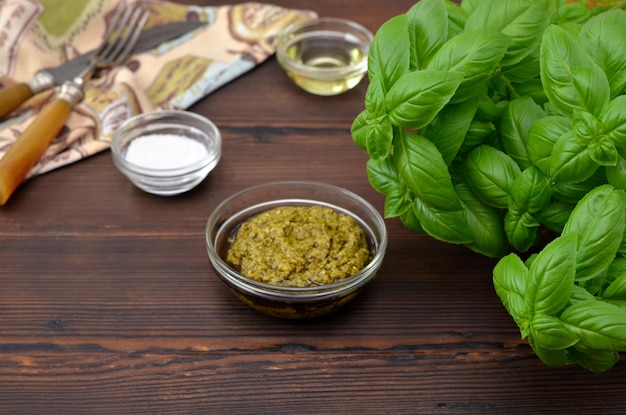 Fresh basil and pesto sauce side by side on wooden table