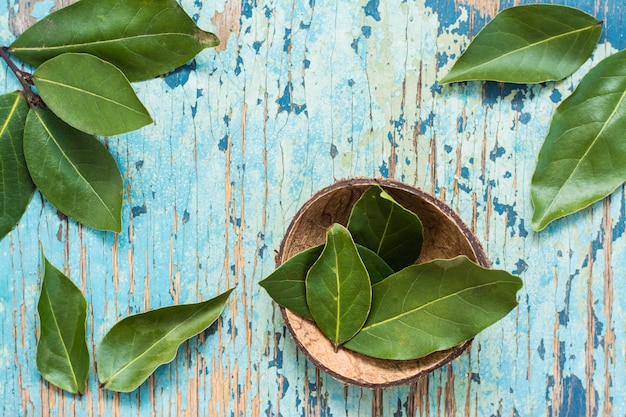 Fresh bay leaves in a wooden bowl on a rustic table. Top view