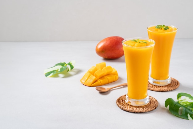 Fresh beautiful delicious mango juice smoothie in glass cup on gray table background