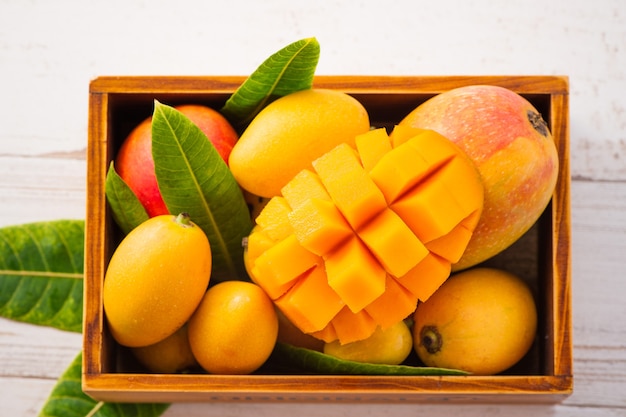 Fresco e bellissimo frutto di mango impostato in una scatola di legno con fette di mango a dadini pezzi su uno sfondo di legno chiaro, copia spazio (spazio testo), vuoto per il testo