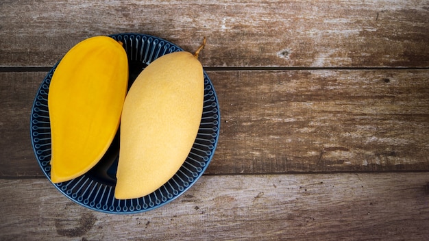 Photo fresh and beautiful sliced ripe mango in a blue ceramic plate with wooden background2