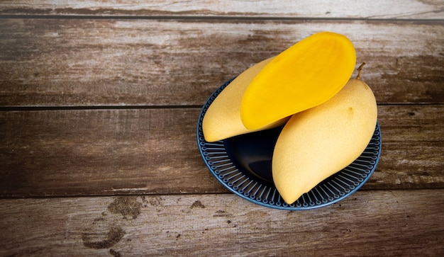 Foto mango maturo affettato fresco e bello in un piatto ceramico blu con fondo di legno