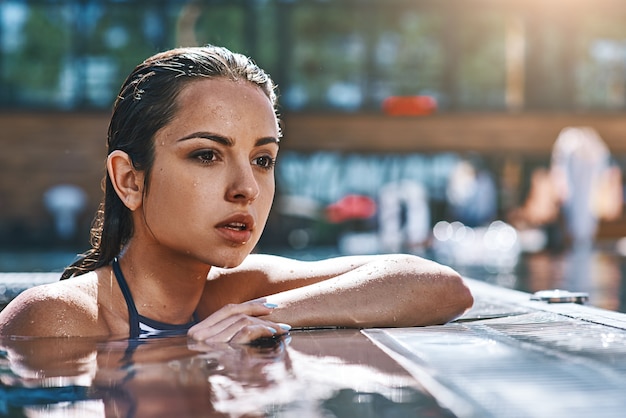 Ritratto di bellezza fresca di giovane donna sexy attraente in costume da bagno che guarda lontano mentre sta in piedi dentro