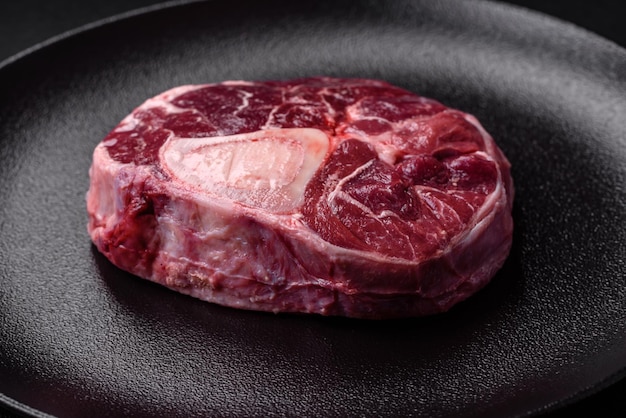 Fresh beef ossobuco steak with salt spices and herbs on textured concrete background