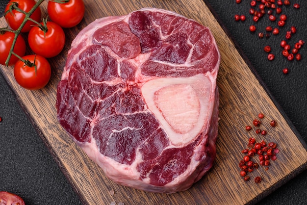 Fresh beef ossobuco steak with salt spices and herbs on textured concrete background