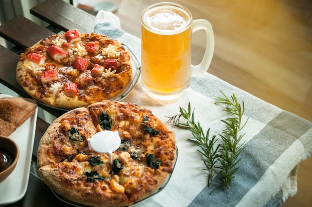 Foto birra fresca nel bicchiere con pizza fatta in casa sullo sfondo in primo piano