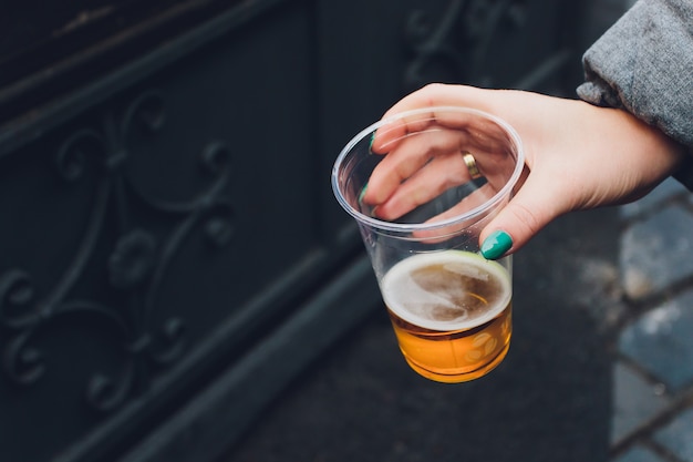 Photo fresh beer in a plastic cup in a hand.