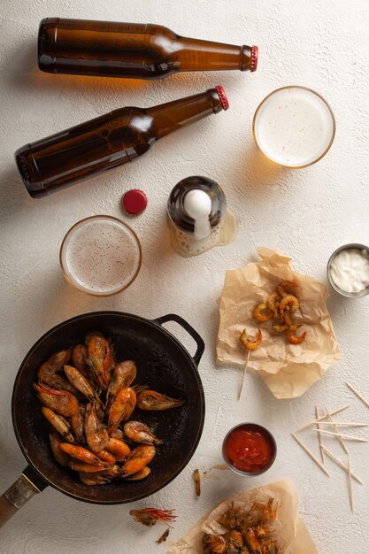 Fresh beer with fried shrimps on a light table, top view