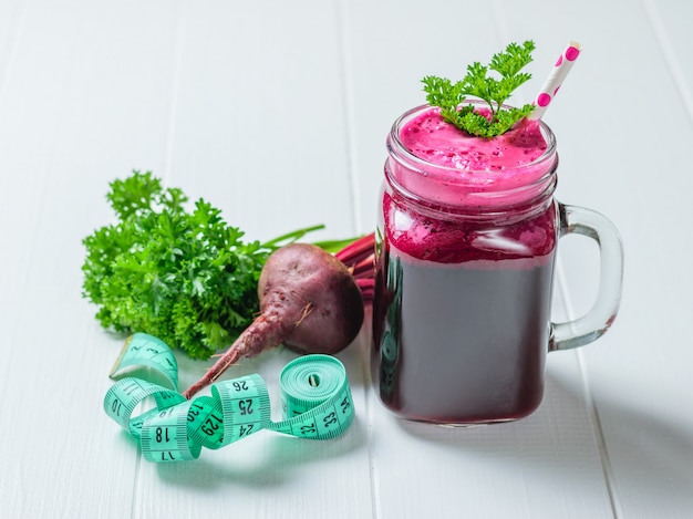 Fresh beetroot smoothie and measuring tape on wooden table