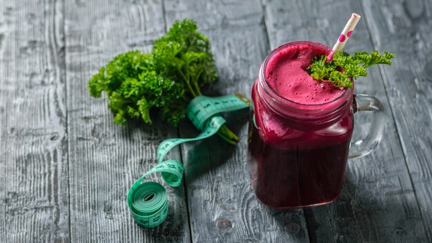 Fresh beetroot smoothie and measuting tape and parsley on black wooden table. The concept of dietary natural food. Vegetarian cuisine. The view from the top.