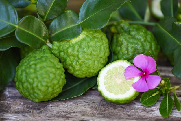 Fresh bergamot fruit and pink flower Kaffir Lime Citrus bergamia with leaf on wooden table Slice bergamot citrus fruit essential oil concept