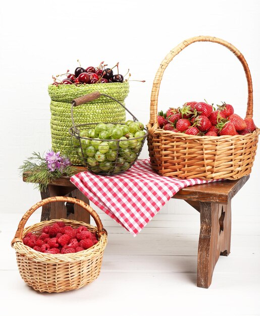 Photo fresh berries in baskets on white wall background