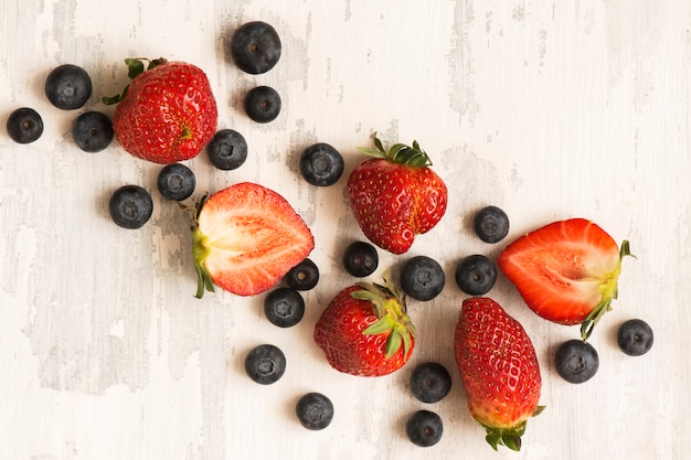 Fresh berries: blueberry and strawberry over white wooden table.