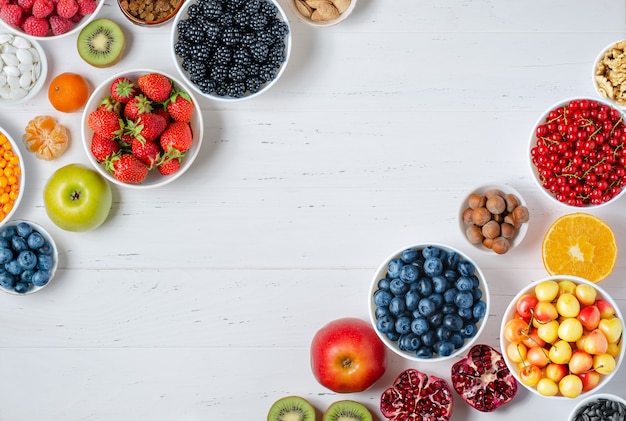 Fresh berries fruits nuts on a white wooden background the concept of healthy eating food contains v