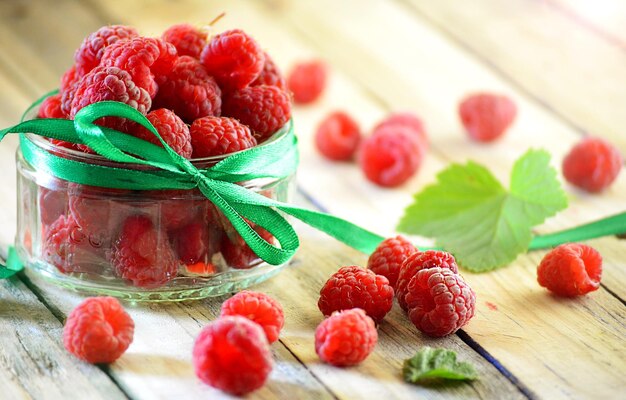 Fresh berries in a glass jar on wooden background