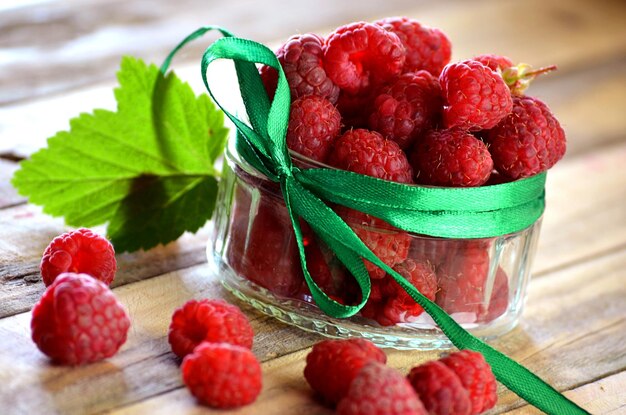 Fresh berries in a glass jar on wooden background