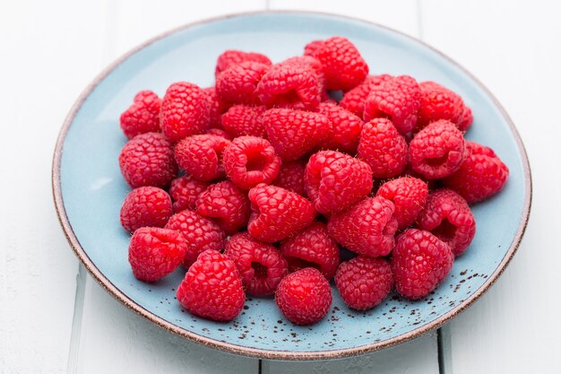 Fresh berries in a plate on a  wooden surface. Flat lay, top view, copy space.