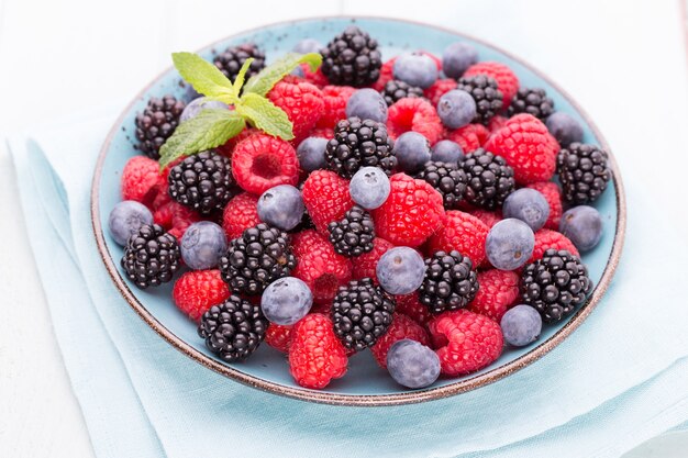 Fresh berries in a plate on a  wooden surface. Flat lay, top view, copy space.