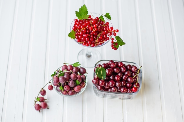キッチンの木製テーブルの上のガラス皿に新鮮な果実赤スグリ グーズベリー チェリー