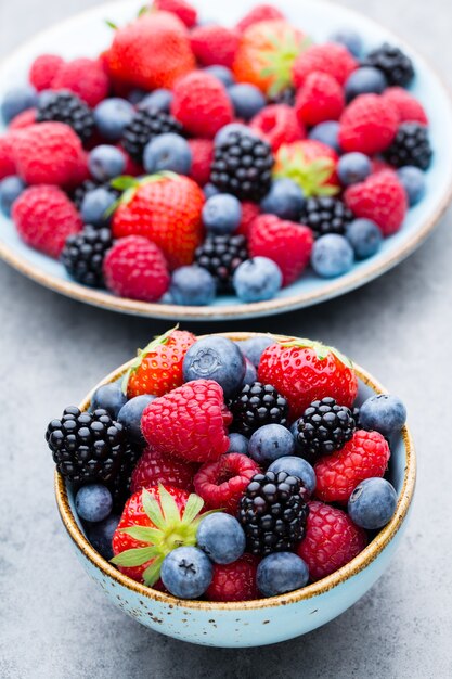 Fresh berries salad in a plate on a  wooden background. Flat lay, top view, copy space.