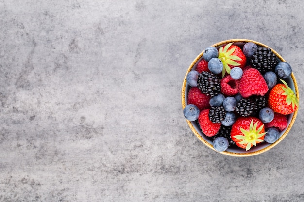 Fresh berries salad in a plate on a  wooden background