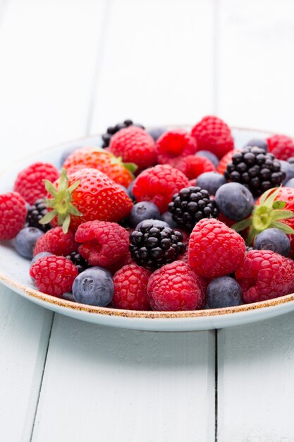 Fresh berries salad in a plate on a  wooden surface. Flat lay, top view, copy space.