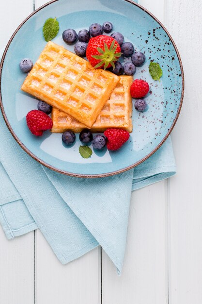 Fresh berries salad in a plate on a  wooden surface. Flat lay, top view, copy space.