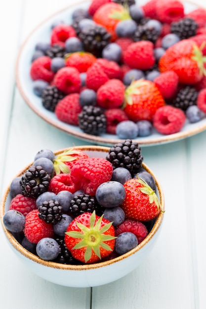 Fresh berries salad in a plate on a  wooden surface. Flat lay, top view, copy space.
