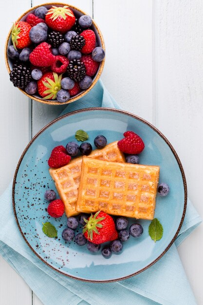 Fresh berries salad in a plate on a  wooden table. Flat lay, top view, copy space.