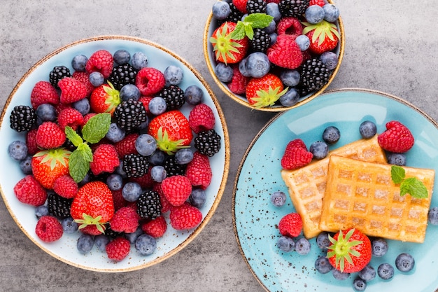 Fresh berries salad in a plate on a wooden table. Flat lay, top view, copy space.