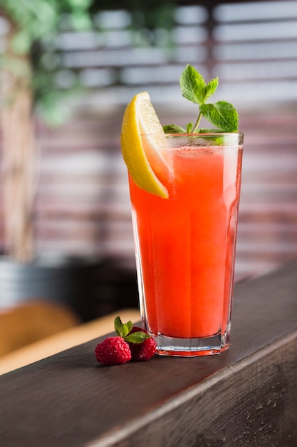 Fresh berry cocktail in a tall glass with a slice of lemon and mint