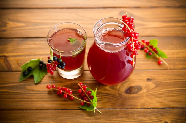 Fresh berry juice from red and black currant on a wooden table