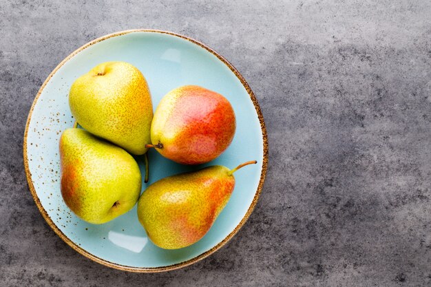 Fresh bio pear with leaves on the plate. Gray stone table.