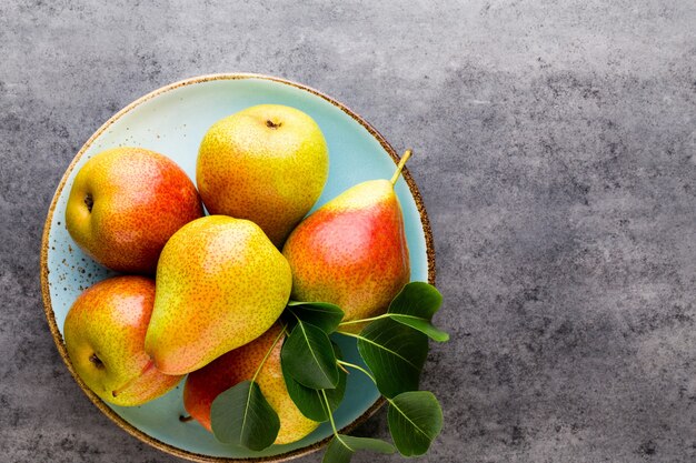 Fresh bio pear with leaves on the plate. Gray stone table.