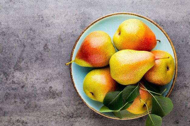 Fresh bio pear with leaves on the plate. Gray stone table.