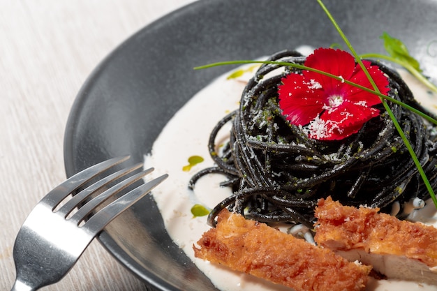 Fresh black tagliolini pasta with chicken in herbs