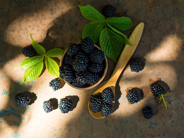 Fresh blackberries in a wooden bowl and spoon on an old table