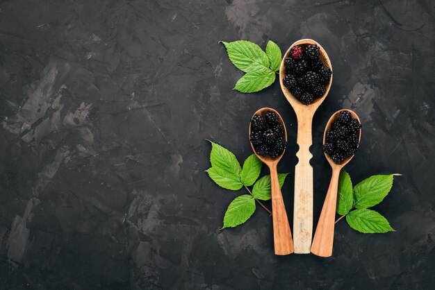 Fresh blackberry in a spoon On a black stone background Top view Free space for text