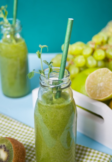 Fresh blended green smoothie in glass small bottles with fruit and vegetables . Health and detox concept.