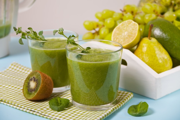 Fresh blended green smoothie in glasses with fruit and vegetables . Health and detox concept.