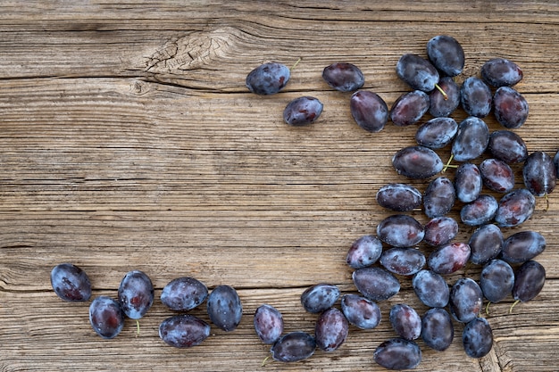 Fresh blue plums on old wooden table