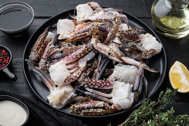 Fresh blue swimming crab Horse crab, Blue crab, Flower crab claws set, on plate, on black wooden table