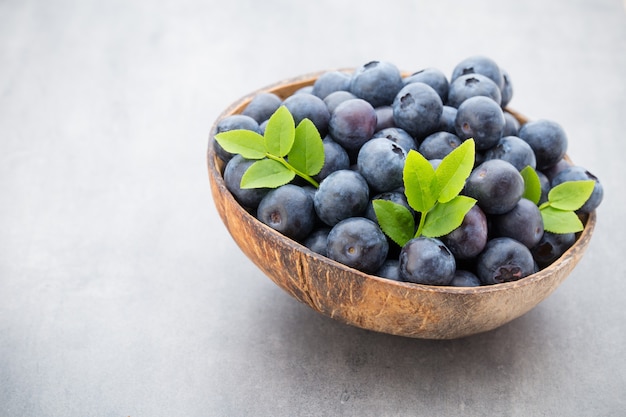 Mirtilli freschi cocco naturale in una ciotola su grigio.