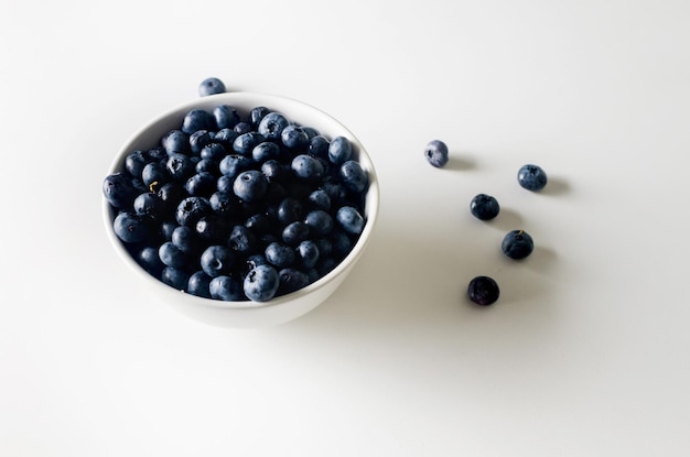 Fresh blueberries in white bowl on white table