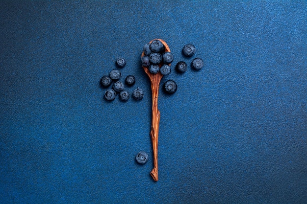 Foto mirtilli freschi in un cucchiaio di legno. bacche su sfondo blu. vista dall'alto.