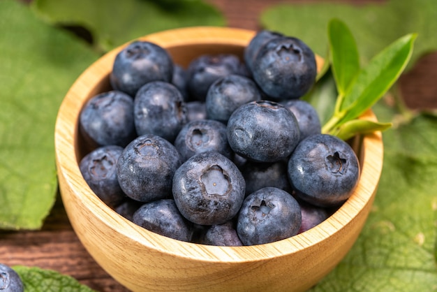 Fresh Blueberries on wooden tray with green leaves background Fresh Blueberries