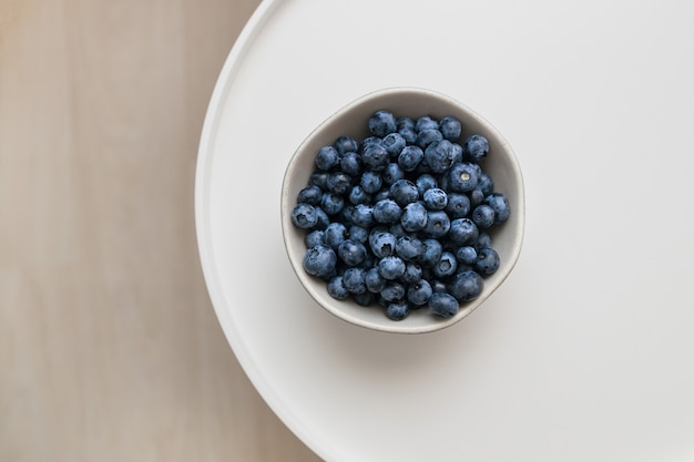 Fresh blueberry antioxidant organic superfood on a white coffee table, top view,healthy nutrition concept.