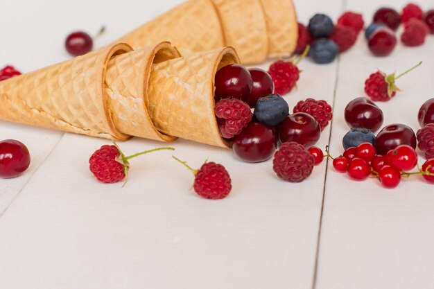 Fresh blueberry, blackberry and raspberry in waffle cone on wooden white